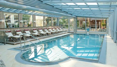 a large swimming pool with chairs in a building at Wellness & Landhotel Prinz- Wellness & Romantik in Anger