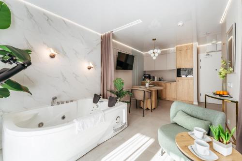 ein Wohnzimmer mit einer großen Badewanne und eine Küche in der Unterkunft Apartamenty z Jakuzzi Perłowa Przystań Rent Kołłątaja in Kołobrzeg