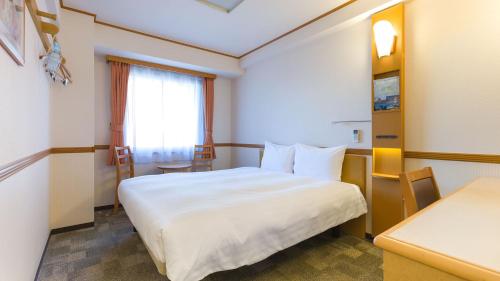 a hotel room with a white bed and a window at Toyoko Inn Saitama Toda koen eki Nishi guchi in Toda