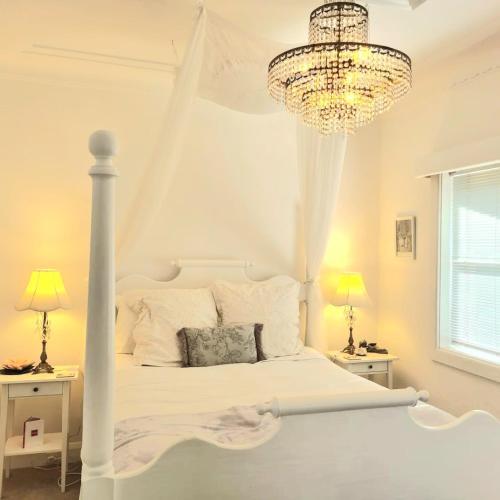 a bedroom with a white bed and a chandelier at Dalia's Blue Mountain Retreat in Katoomba