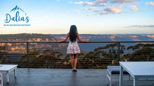 a woman standing on a balcony looking at the view at Dalia's Blue Mountain Retreat in Katoomba