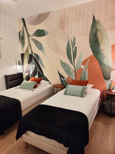 - 2 lits dans une chambre avec une fresque murale dans l'établissement Villa Papillon***. Location appartement 1er étage., à Ronce-les-Bains