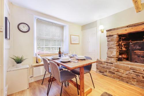 a dining room with a table and a fireplace at Host & Stay - Batemill Cottage in Birch Vale