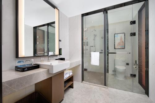 a bathroom with a sink and a shower and a toilet at Hilton Garden Inn Jiujiang Changhong Avenue in Jiujiang