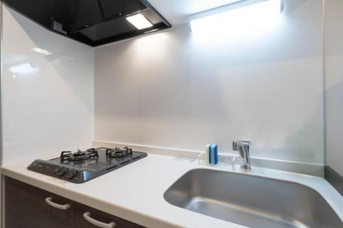 a kitchen with a sink and a stove at Curasion Oyodonaka in Osaka