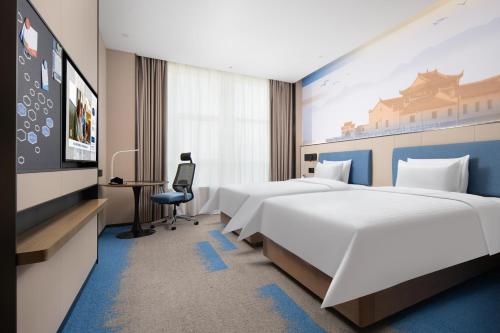 a hotel room with two beds and a tv at Hilton Garden Inn Jiujiang Changhong Avenue in Jiujiang