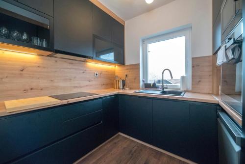 a kitchen with black cabinets and a window at Urban Cozy Apartments Zagreb in Zagreb