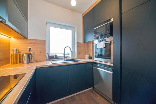a kitchen with black cabinets and a sink and a window at Urban Cozy Apartments Zagreb in Zagreb