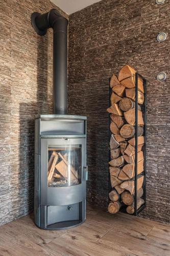a stove with a pile of logs next to a wall at Dream Holiday z Sauna i jacuzzi Lovely Krynica Zdrój in Florynka