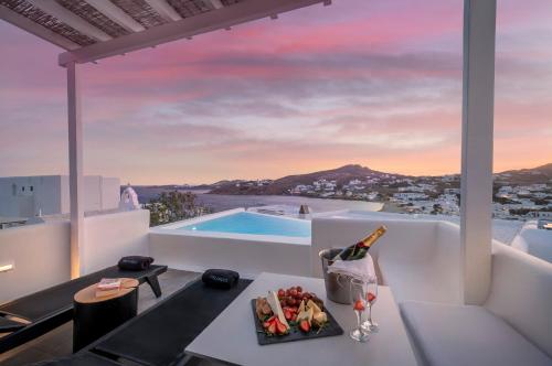 a villa with a pool and a table with a bottle of wine at Deliades Hotel in Ornos