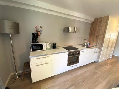 eine Küche mit weißen Schränken und einer weißen Mikrowelle in der Unterkunft BergHerzl - Braunlage in Braunlage