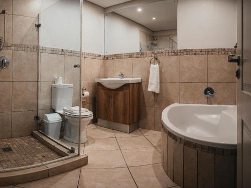 a bathroom with a sink and a tub and a toilet at Cape Panorama Lodge in Panorama