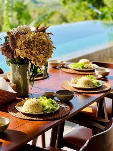 a wooden table with plates of food and flowers on it at Amaya Kampot Homestays in Kampot