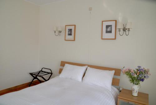 a bed room with a white bedspread and a white wall at Guesthouse Les Tilleuls in Fleurus