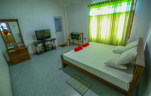 a bedroom with a large bed and a television at Janali Homestay in Kandy