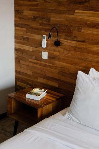 a bed with a wooden headboard and a table with a book at Surf Motel in Canggu