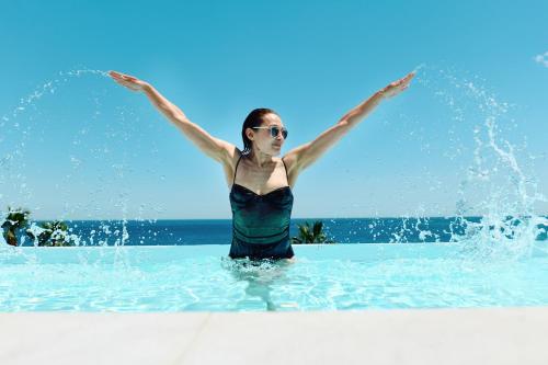a woman is standing in the water with her arms up at MARINO WELLNESS in Ali Terme