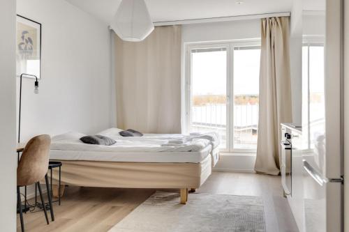 a white bedroom with a bed and a window at Studio Apartments Pukkila in Turku
