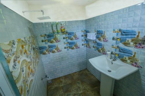 a blue tiled bathroom with a sink and a shower at Janali Homestay in Kandy
