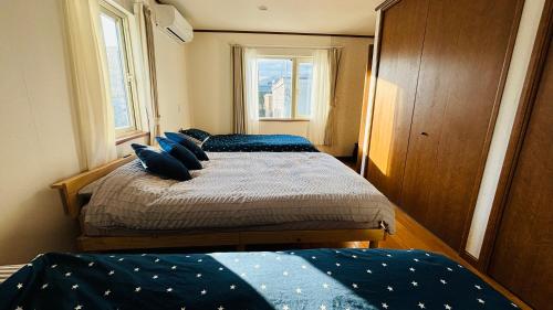 two beds in a small room with two windows at SecondHouse Otaru Garden in Otaru