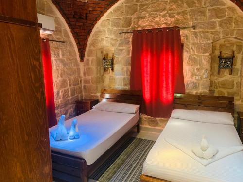 two beds in a room with red curtains at palm shadow resort in Tunis