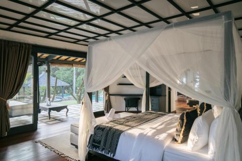 a bedroom with a large bed and a piano at Villa Puri Greenlot Cemagi in Canggu