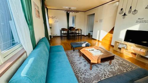 a living room with a blue couch and a table at SecondHouse Otaru Garden in Otaru