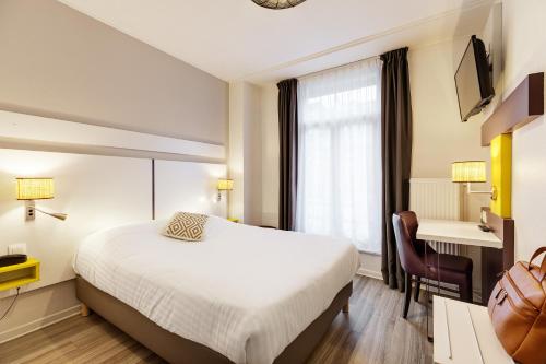 a hotel room with a bed and a desk at Grand Hôtel Lille in Lille