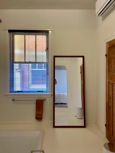 a mirror in a bathroom with a tub and a window at Huis Hector Mechiels ROOM in Sint-Niklaas