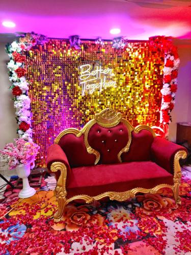a red couch in front of a stage with flowers at Opulence Inn - 500 Meters From Railway Station in Udaipur