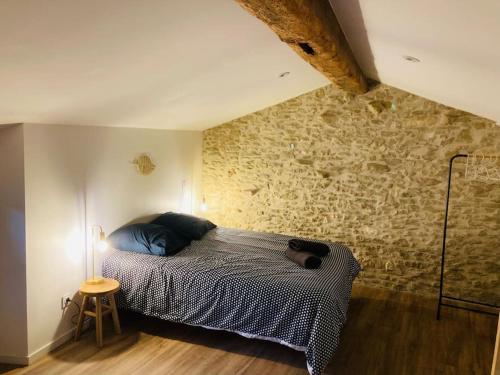 a bedroom with a bed and a stone wall at Charmante Maison l Jardin l Clim in Carbes