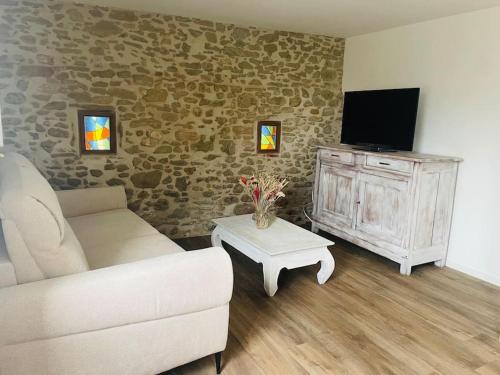 a living room with a couch and a tv at Charmante Maison l Jardin l Clim in Carbes