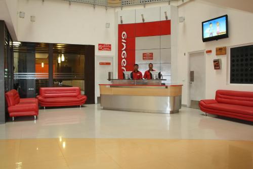 a lobby with red chairs and a counter in a store at Ginger Pantnagar in Pantnagar