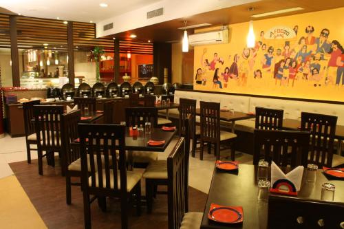 a restaurant with tables and chairs and a painting on the wall at Ginger Pantnagar in Pantnagar