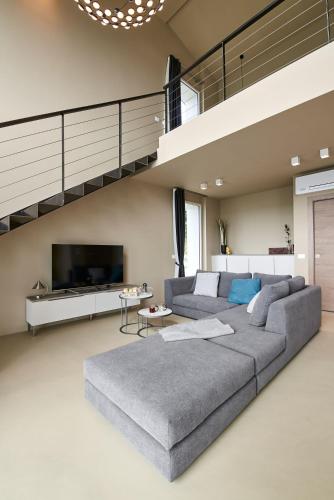 a living room with a gray couch and a staircase at Loft experience Amore o Psyche a Carobais 7 in Roncola