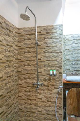 eine Dusche in einem Badezimmer mit einer Steinwand in der Unterkunft Lilac Elevate Inn in Karatu