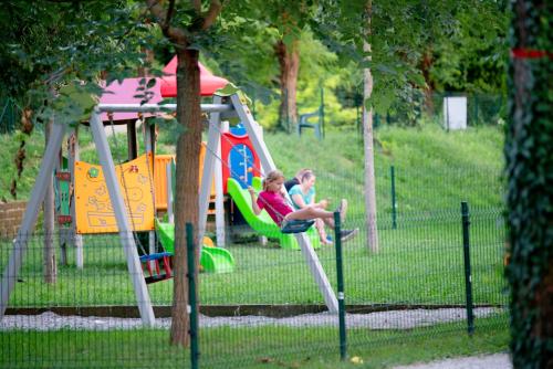 two children playing on a playground in a park at Camping Baia Verde in Manerba del Garda