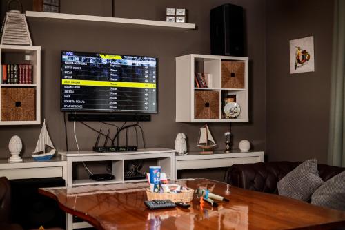 a living room with a table and a large screen tv at Dacha in Astana