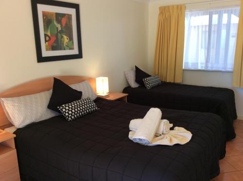 a bedroom with two beds with black sheets at Pelican's Nest in Kalbarri