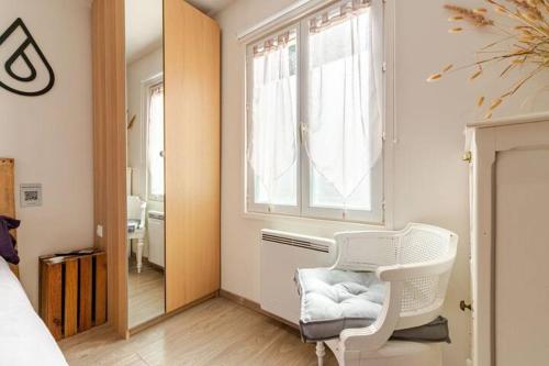 a bedroom with a white chair and a window at Maison au bout du chemin in Gouvieux