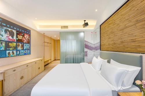a bedroom with a large white bed and a tv at 广州柠下酒店科韵路琶洲会展中心店 in Guangzhou