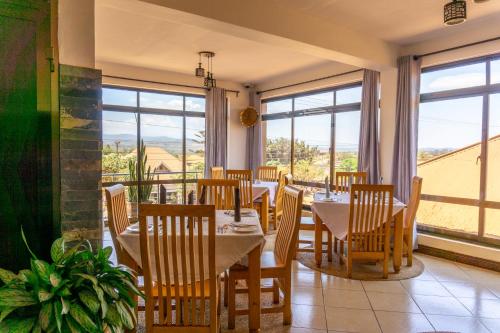a restaurant with tables and chairs and large windows at Lilac Elevate Inn in Karatu