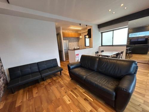 a living room with a leather couch and a kitchen at nico chan house in Chatan