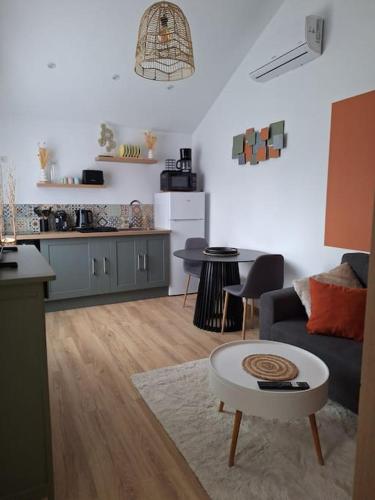 Il dispose d'une cuisine et d'un salon avec un canapé et une table. dans l'établissement Charmante maisonnette équipée, à Caudebec-lès-Elbeuf
