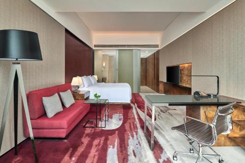 a hotel room with a bed and a red couch at Hilton Guangzhou Tianhe - Free Shuttle Bus and Registration Counter Available during Canton Fair Period in Guangzhou