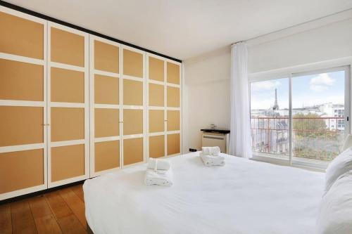 - une chambre avec un grand lit blanc et une grande fenêtre dans l'établissement Penthouse Champs Élysées, vue sur tout Paris et la Tour Eiffel, à Paris
