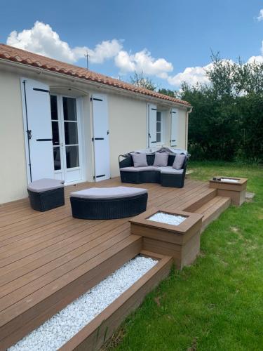 a wooden deck with a couch and chairs on it at Belle maison 6 personnes à 2min du Lac du Jaunay, et 15min des plages Vendéennes in La Chapelle-Hermier
