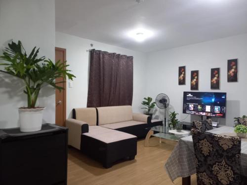 a living room with a couch and a tv at Pine Suites Tagaytay @ RoseAna Staycation in Tagaytay