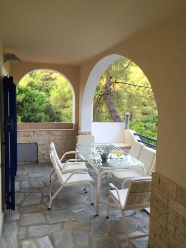 a patio with a table and chairs and two arched windows at Villa Kanapitsa in Skiathos Town