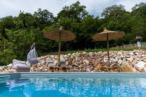 a pool with two umbrellas and chairs next to a rock wall at Complex Butoaiele Transilvaniei - Cazare & SPA - Natura - Relaxare in Mediaş